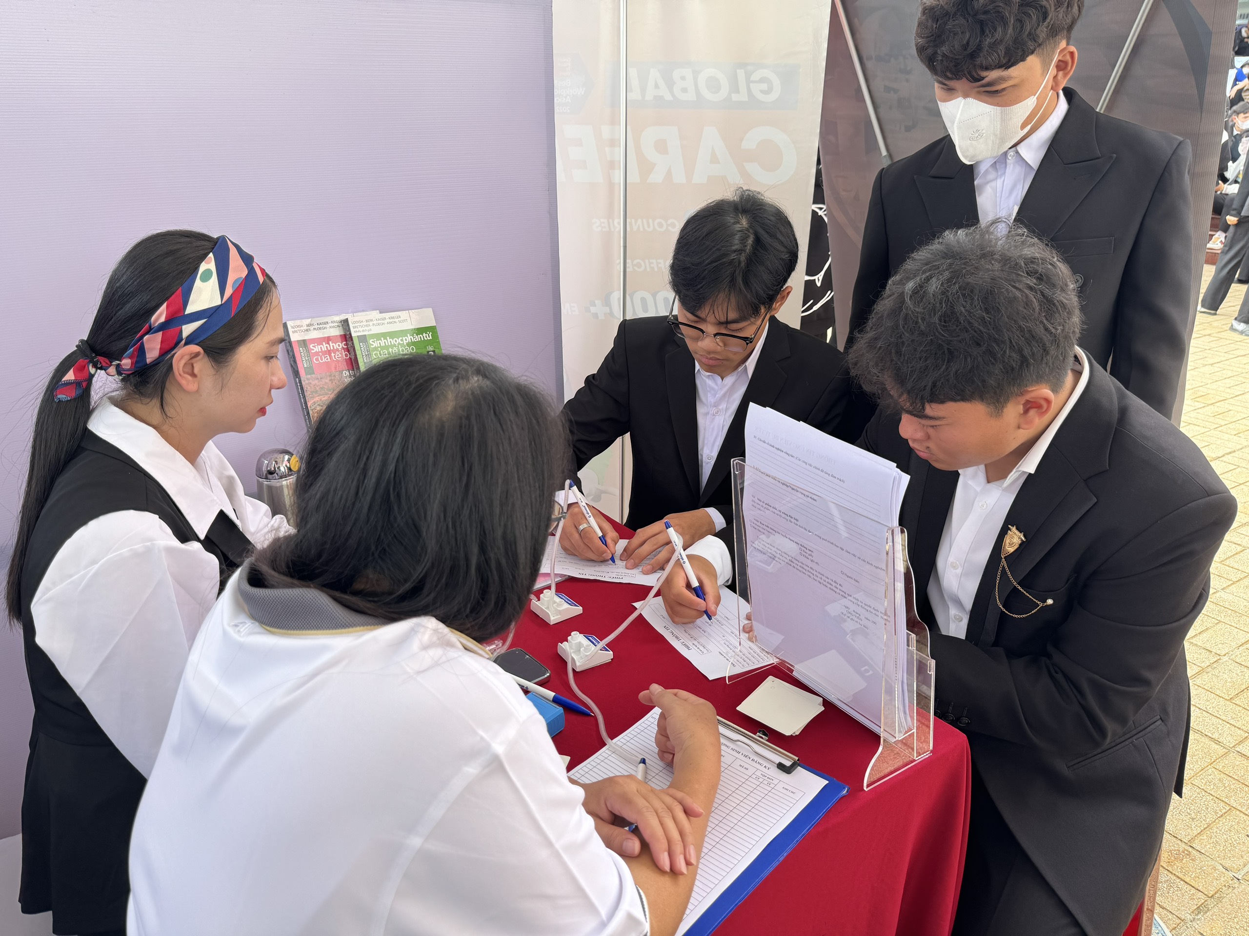 Students are completing the application forms and receiving recruitment consultations at the booth.